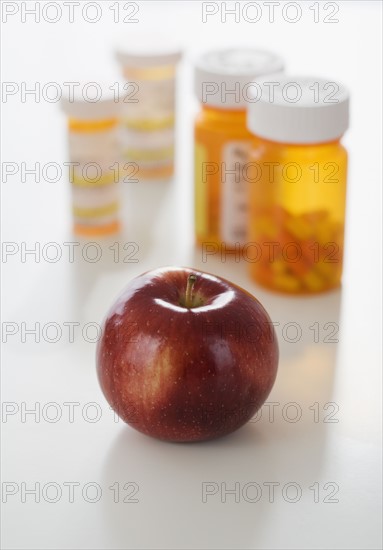 Apple in front of medication bottles.