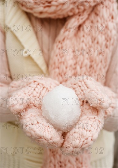 Person holding snowball in gloved hands.