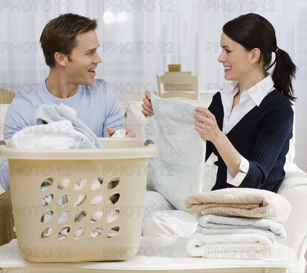 Couple folding laundry in livingroom.