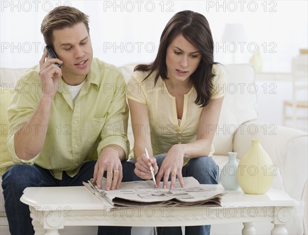 Couple reading classifieds in newspaper.
