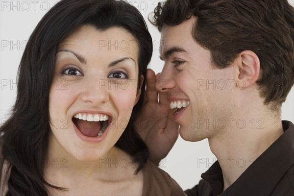 Man whispering in girlfriend's ear.