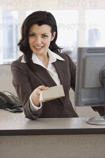 Woman handing paperwork over counter.