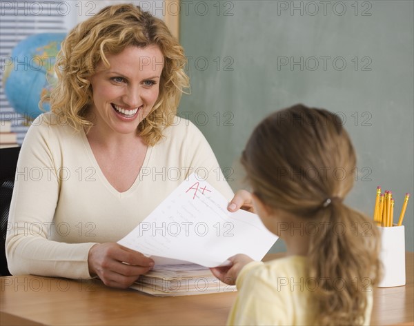 Female teacher handing paper back to student.