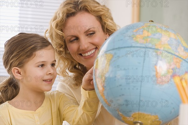 Mother and daughter looking at globe.