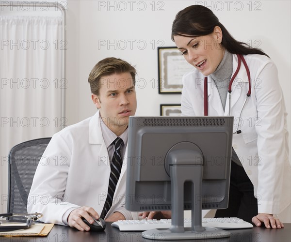 Doctors looking at computer in office.