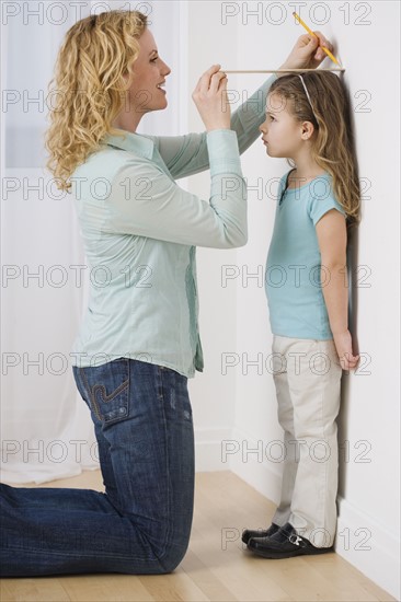 Mother marking daughter’s height on wall.