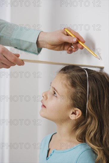 Mother marking daughter’s height on wall.