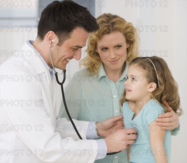 Male doctor listening to girl’s heart.