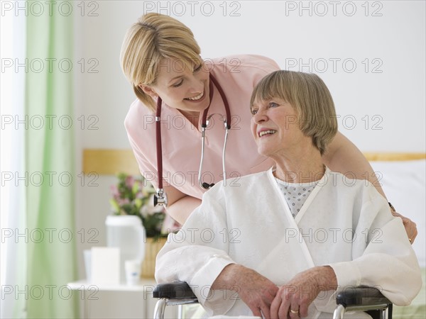 Nurse pushing senior woman in wheelchair.