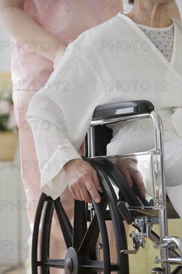 Nurse pushing senior woman in wheelchair.