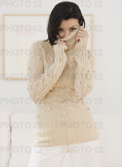 Woman pulling sweater over face.