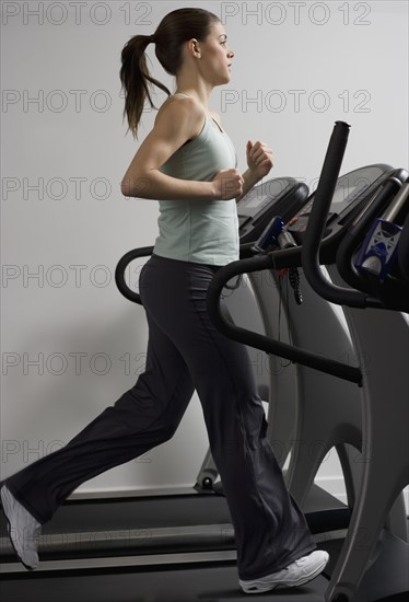 Woman running on treadmill at health club.