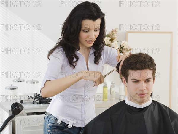 Female hair stylist cutting man’s hair.