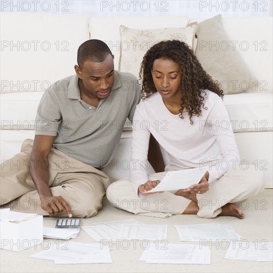 Couple paying bills on floor.