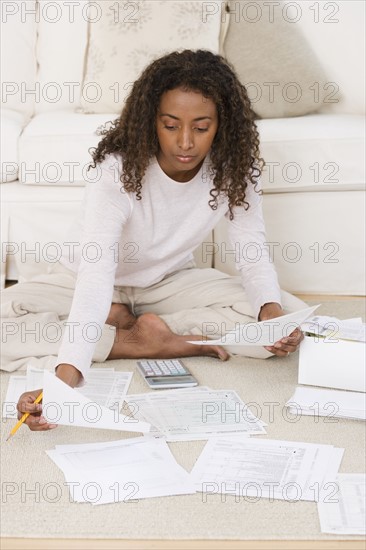 Woman paying bills on floor.