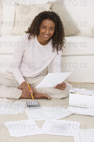 Woman paying bills on floor.