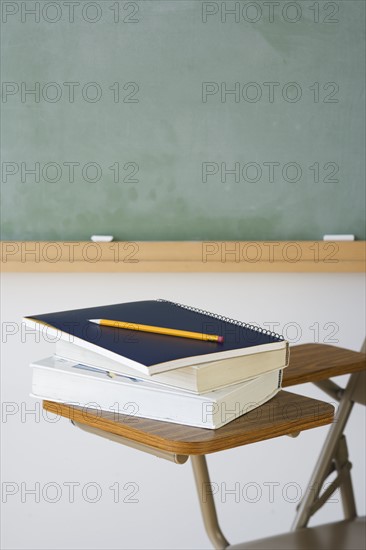 Books and pencil on desk in classroom.