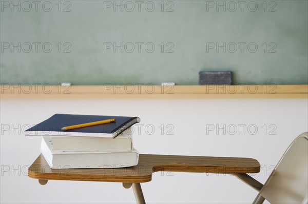 Books and pencil on desk in classroom.