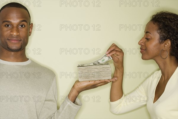 Woman taking money from stack in husband’s hand.