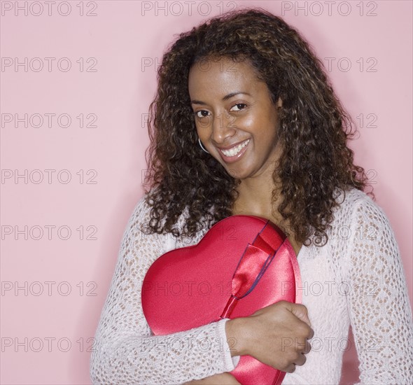 Portrait of woman holding heart shaped box.