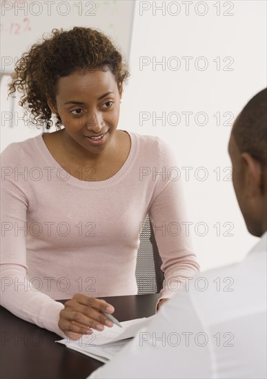 Businesswoman discussing paperwork with coworker.