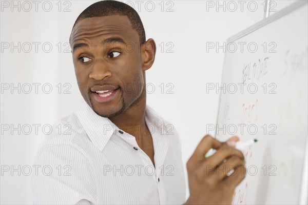 Businessman writing on whiteboard.