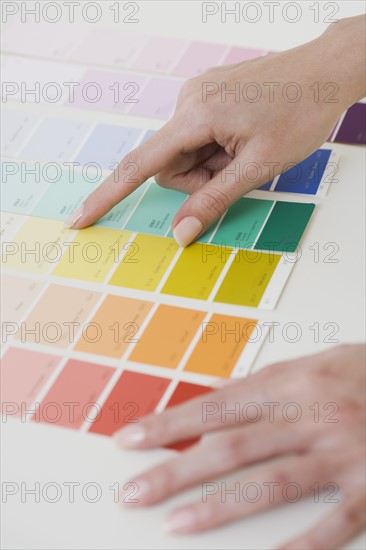 Close up of woman comparing paint swatches.