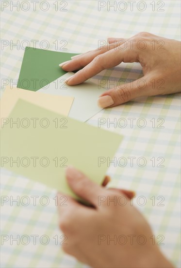 Close up of woman comparing paint swatches.