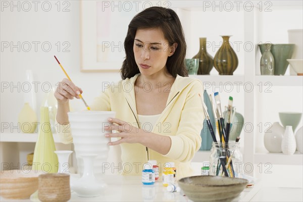 Female artist painting pottery.