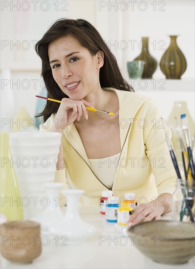 Female artist painting pottery.