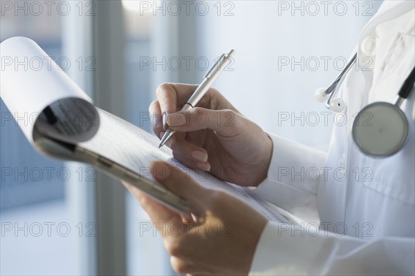 Close up of doctor writing on medical chart.