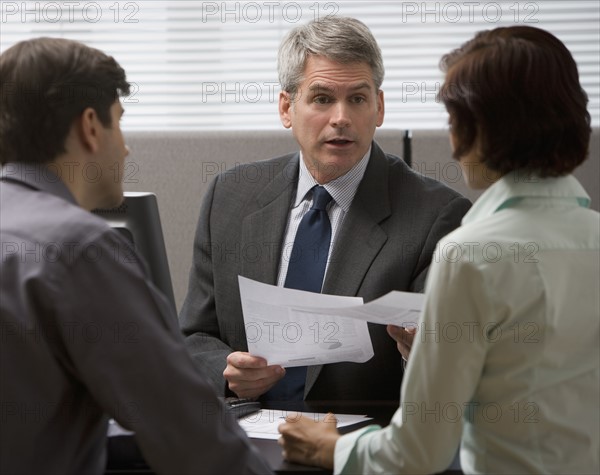 Businessman talking to couple in office.