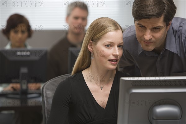 Businessman and businesswoman looking at computer.