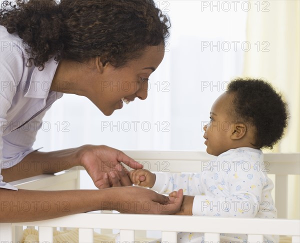 Mother smiling at baby in crib.