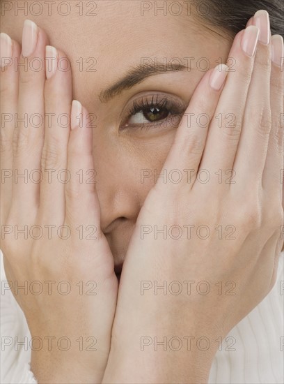 Close up of woman covering face with hands.