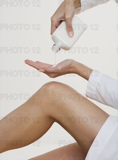 Woman pouring lotion into hand.