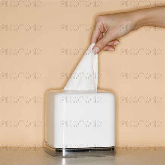 Woman pulling tissue out of box.