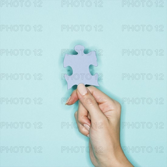 Woman holding jigsaw puzzle piece.