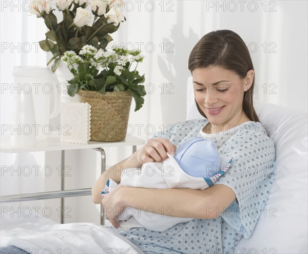 Mother smiling at newborn baby in hospital.