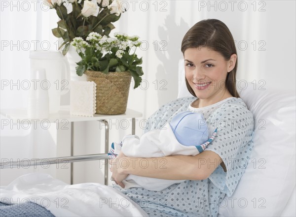 Portrait of mother holding newborn baby in hospital.