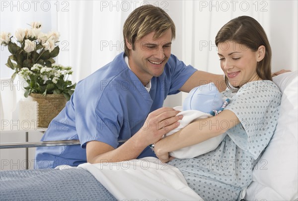 Parents smiling at newborn baby in hospital.