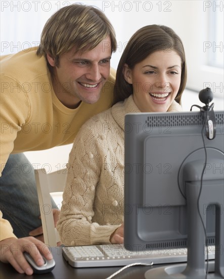 Couple smiling at webcam on computer.