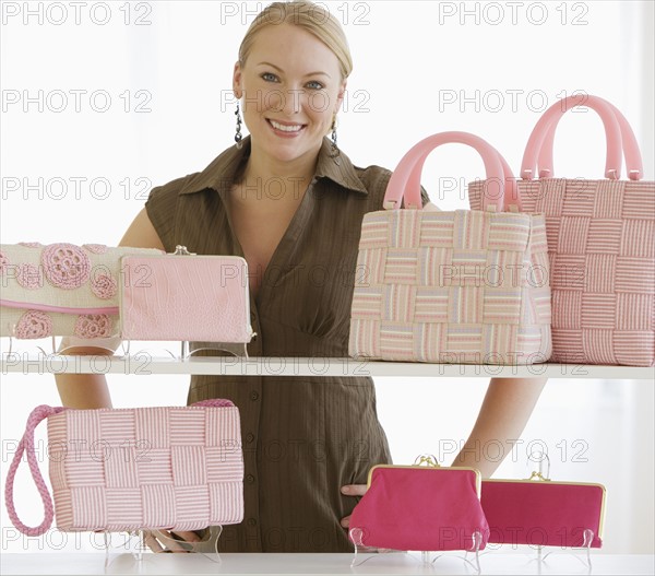 Woman behind shelves of purses.