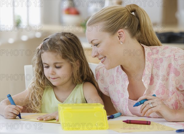 Mother and daughter coloring at table.