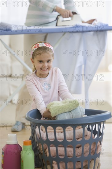 Girl doing laundry with mother.
