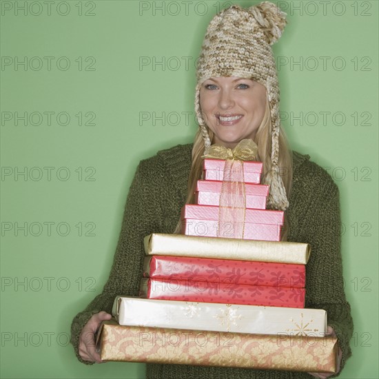 Woman holding stack of Christmas gifts.