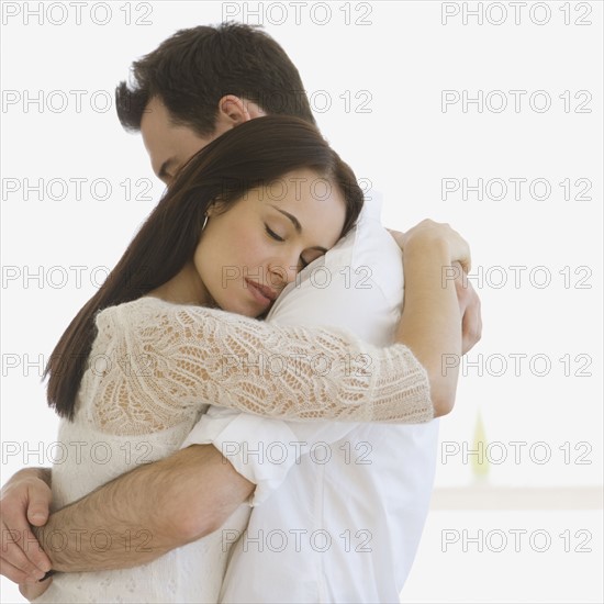 Couple hugging indoors.