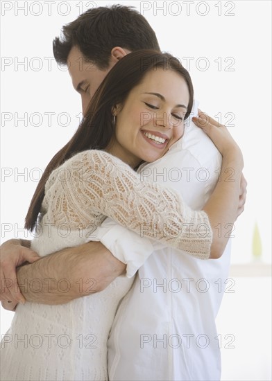 Couple hugging indoors.