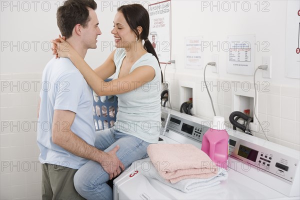 Couple hugging in laundry room.