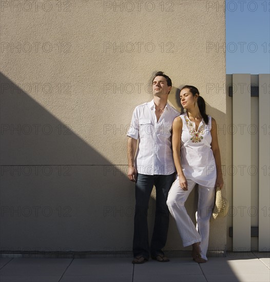 Woman leaning on wall in sunlight.